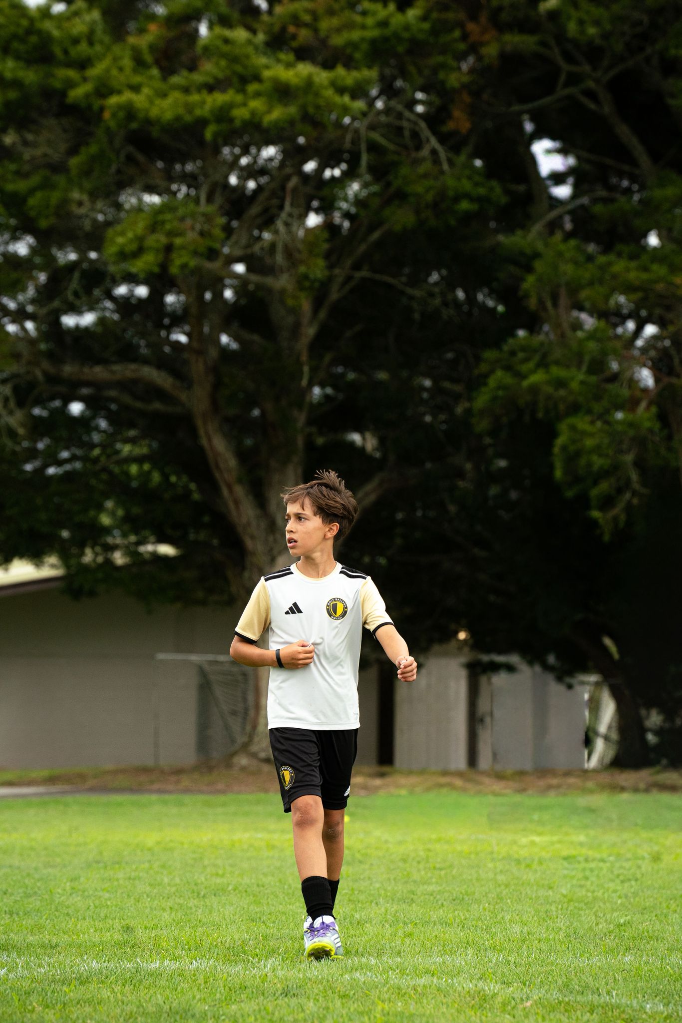 Only Ballers player jogging on the pitch in white and gold kit