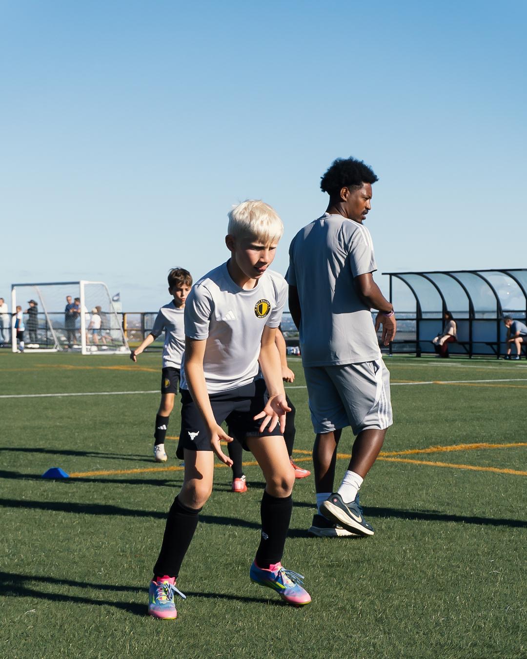 Coach Zemi training with player on the pitch